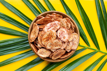 Banana chips on green leave with yellow background.