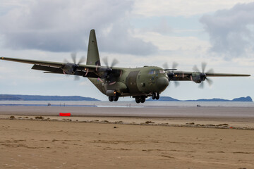 Fototapeta na wymiar A Royal Air Force Lockheed C-130J 'Super Hercules' performing tactical landings and takeoffs from the public beach at Cefn Sidan Sands in West Wales.