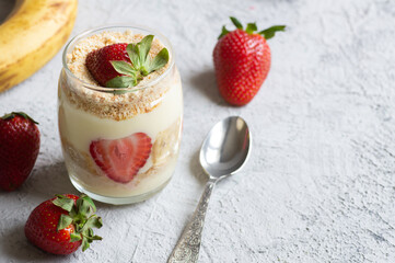 Magnolia dessert with fresh bananas and strawberries in glass cup, homemade milky dessert concept