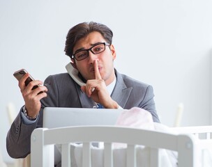 Young businessman trying to work from home caring after newborn
