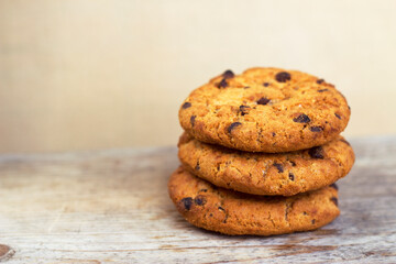 Three chocolate chip cookies on wooden table - close up with copy space. Homemade sweet dessert for kids.