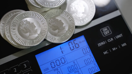 Silver investment coins weighing on precise digital scales. Money, investor and finance and economy concept. 