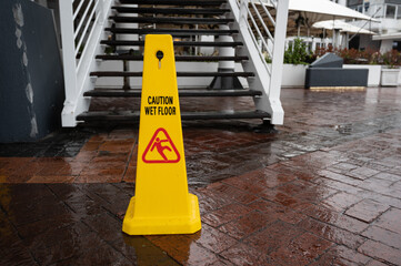Wet floor sign in front of the wet ladder during rain