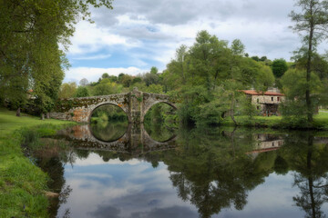 Fototapeta na wymiar Old Romanesque stone bridge over the Arnoia river in the beautiful village of Allariz, Galicia.