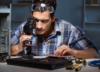 Repairman trying to repair laptop with miscroscope