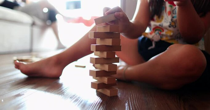 Child playing with wooden building blocks. Kid trial and error play