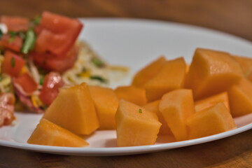 white plate with mediterranean salad and cantaloupe