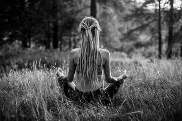 Yoga woman in lotos pose in the pine forest. Black and white photo.