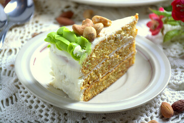 Slice of homemade carrot cake with cream cheese frosting on white plate. Selective focus. 