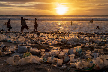 Tourists walk along sand covered in plastic rublish in at Kuta Beach in Bali, Indonesia