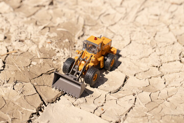 渇水でひび割れた地面とホイールローダー