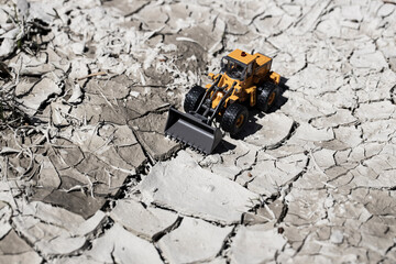 渇水でひび割れた地面とホイールローダー