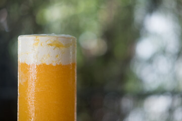 Healthy smoothie orange juice in a stemless glass with milk cream on top