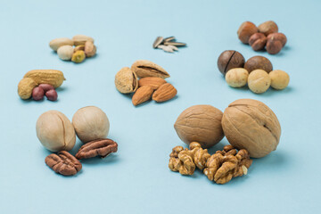 A few peeled and unpeeled nuts on a light blue background.