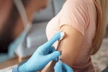 Closeup male doctor making vaccination injection dose in female shoulder