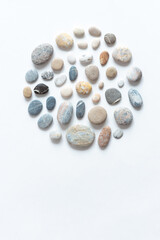Round composition of various pebbles on a white background. Minimalistic natural background for invitation or greeting card with copy space.