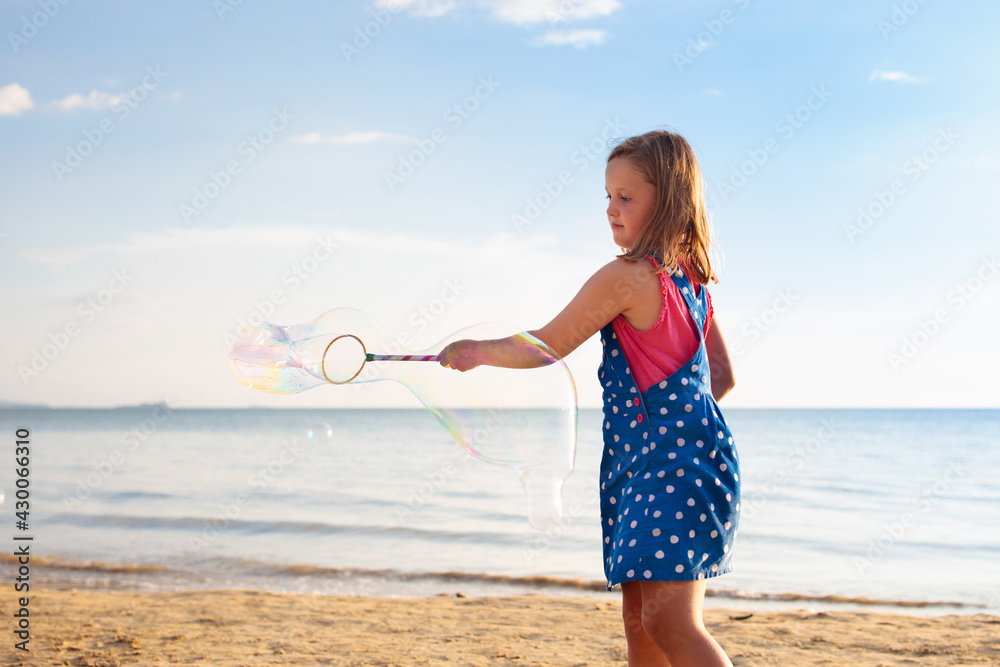 Wall mural kids blow bubble at beach. child with bubbles