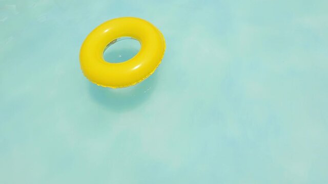 yellow dounut ring in blue water, swimingpool in summer sunny day. fresh water in the resort. yellow swimming pool ring float in blue water. relaxing in the swimming pool on a summer hot day. 