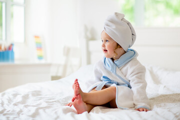 Baby girl in towel after bath. Infant care.