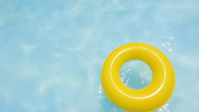 yellow dounut ring in blue water, swimingpool in summer sunny day. fresh water in resort. yellow swimming pool ring float in blue water. relaxing in the swiming pool in a summer hot day. 