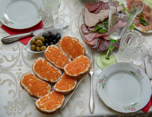 Dinner table served with cold meats, sandwiches with red caviar and olives