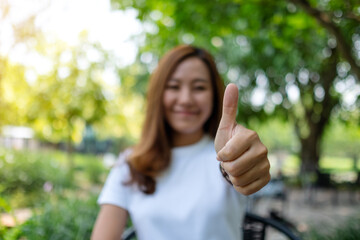 Closeup image of a woman making and showing thumbs up hand sign