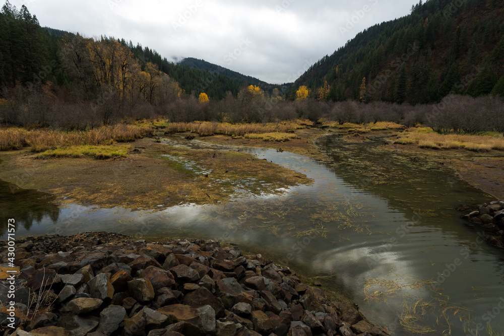 Wall mural autumn landscape. water stream, hills and sky reflection. lonesome creek in autumn season. coeur d`a