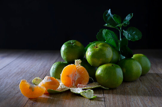 Still life of Fresh sweet tangerine on the wooden plank and dark wall