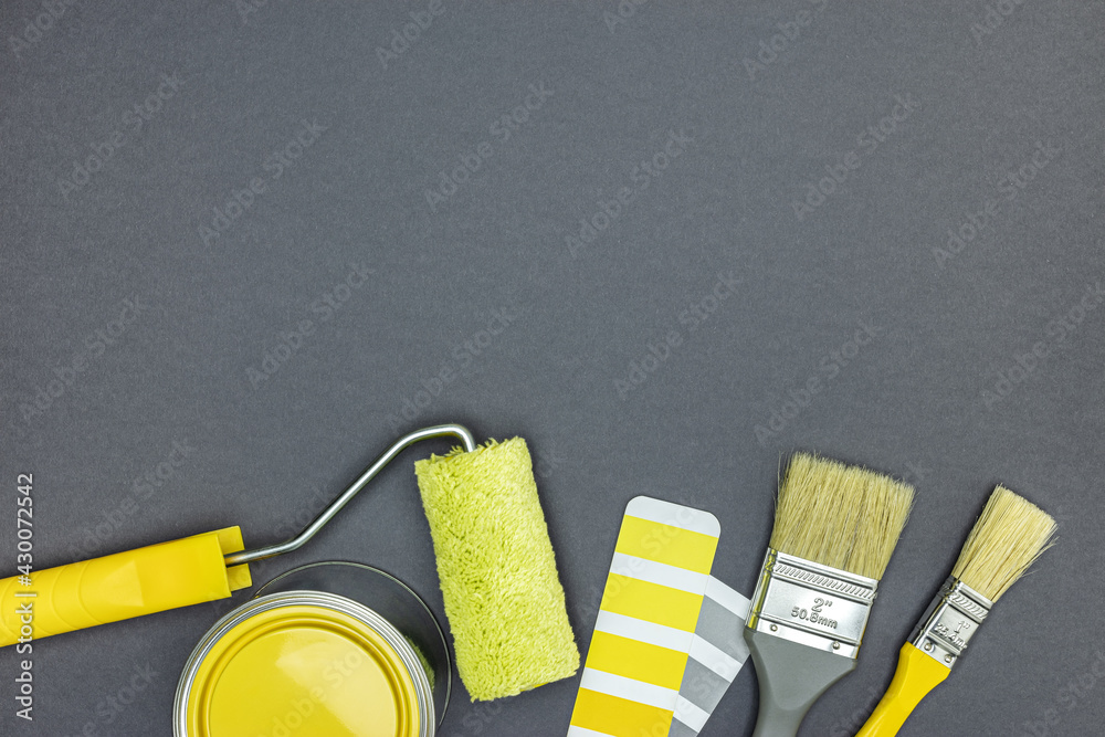 Wall mural tools for house improvement works. brushes, paint roller, paint can and color swatches on gray  background. top view