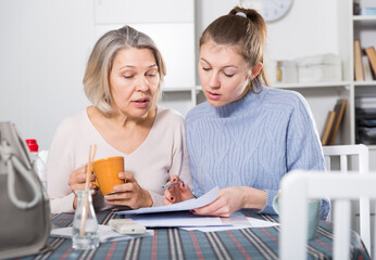 Senior woman with help of her daughter filling bills at home