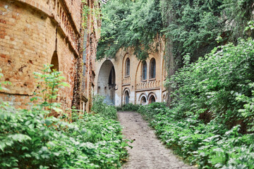 Road with puddles after rains, old ancient abandoned buildings with brick green plants, beautiful landscape beautiful nature, traveling, tourism.