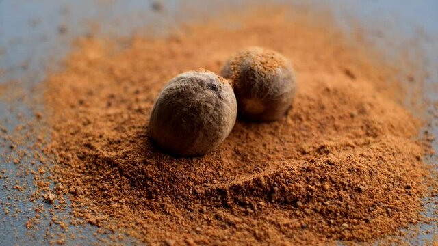 Powder nutmeg. Two whole nutmegs in powder on black slate background