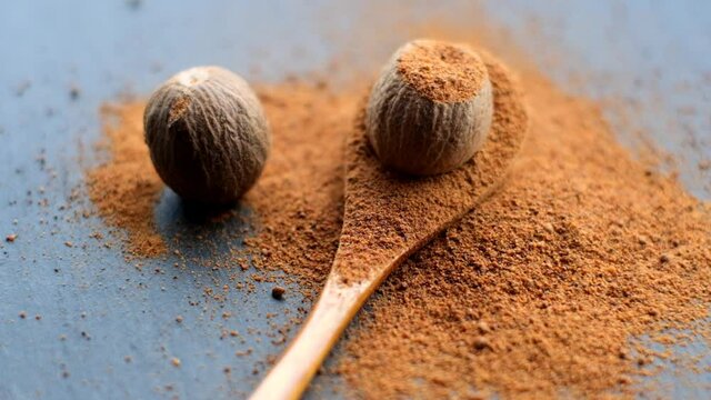 Nutmeg.Grated nutmeg. Whole nutmeg and ground nutmeg in a wooden spoon on a black slate background