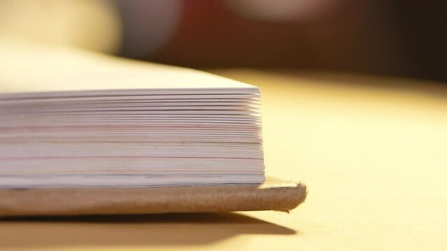 Flipping book pages close up. Looking through the corner of the book on table.