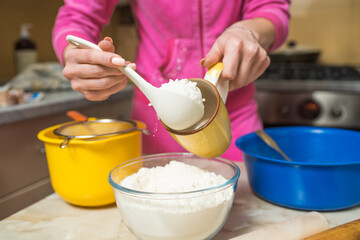Female hands pouring flour into a cup. Cooking at home