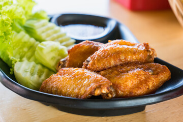 Deep fried chicken wings and green fried herb leaves, selective focus of Thai meal.