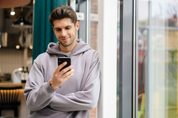Happy young brunette man holding mobile phone