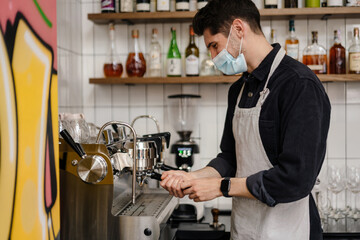 Young white brunette man in apron and protective mask