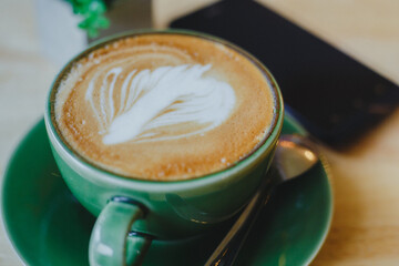cups of latte coffee with latte art on wooden background. Beautiful foam, greenery ceramic cups