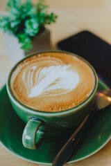 cups of latte coffee with latte art on wooden background. Beautiful foam, greenery ceramic cups