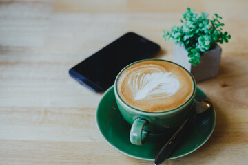 Obraz na płótnie Canvas cups of latte coffee with latte art on wooden background. Beautiful foam, greenery ceramic cups