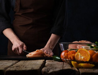 Chef cuts chicken fillet for cooking. Ingredients background. Culinary Recipes and Food Preparation Restaurant Business