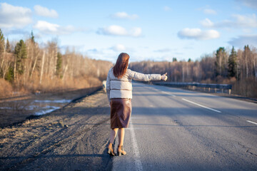 The girl stops the car on the highway with her hand. 