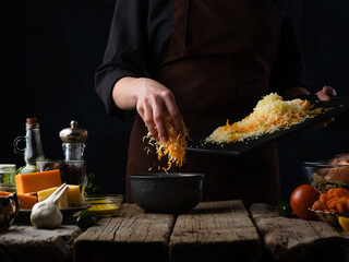The chef rubs different types of cheeses for cooking pizza or other dish. Against the background of...