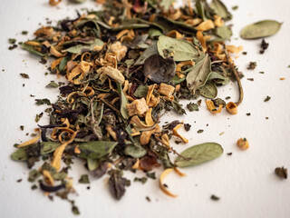 Organic herbal tea in a glass jar with dried herbs scattered around on a white background in the morning light