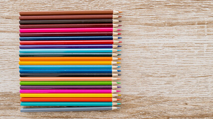 Colorful colored pencils arranged on a wooden table