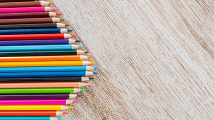 Colorful colored pencils arranged on a wooden table