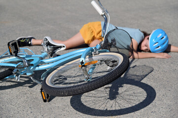 Young girl (female age 10-11) fallen of a bicycle laying down beside her bike unconscious on paved...