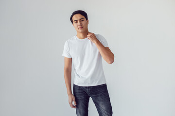 Attractive asian man in white t-shirt stands on white background.