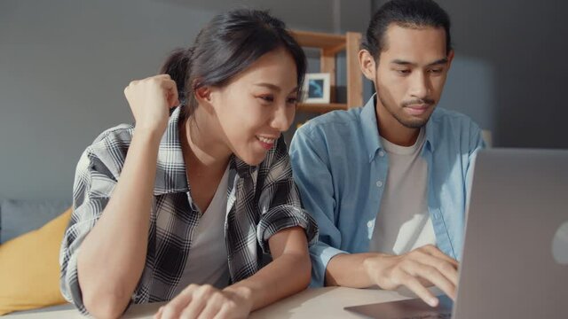 Success asia young couple man and woman thrilled excited maready bank loan agreement for new house online in laptop computer at home, happy husband and wife happy with finance investment good news.
